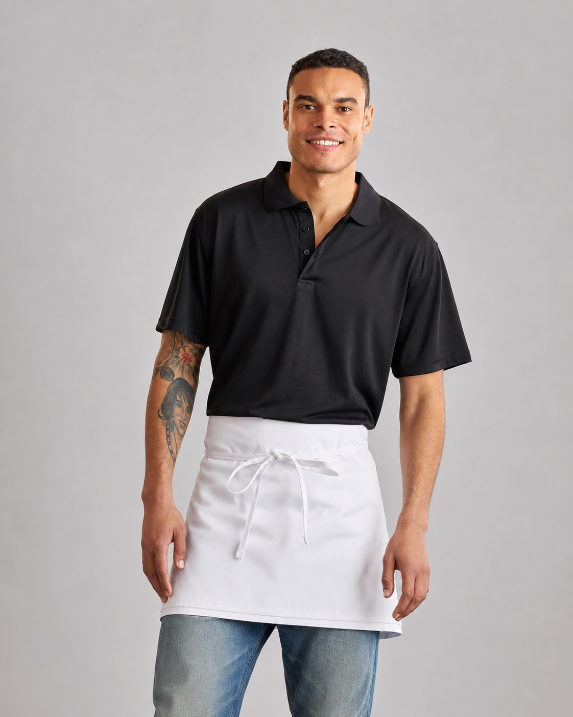 Man wearing a black polo shirt and white apron on a gray background